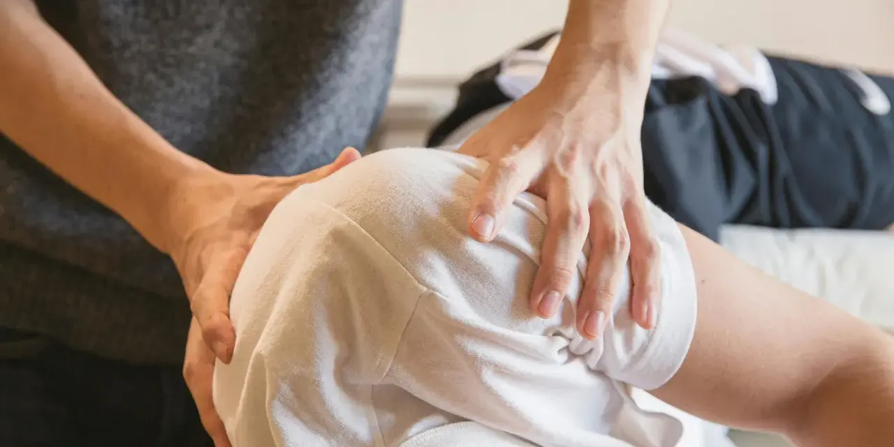 Fizjoterapeuta bada ramię pacjenta, szukając odpowiedzi na pytanie, czy uszkodzony nerw się regeneruje.