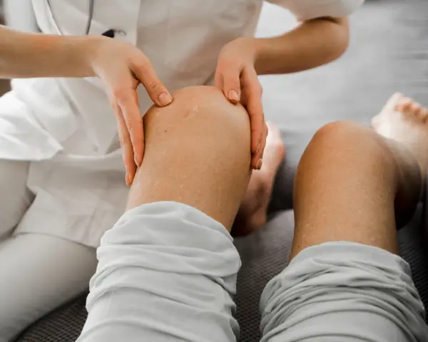 Fizjoterapeuta bada kolano pacjenta, sprawdzając stan nerwów nogi.