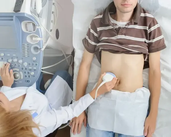 Lekarz wykonuje badanie USG brzucha pacjenta, sprawdzając jego narządy wewnętrzne. Może to pomóc w diagnostyce problemów z wyrostkiem kolczystym C7.