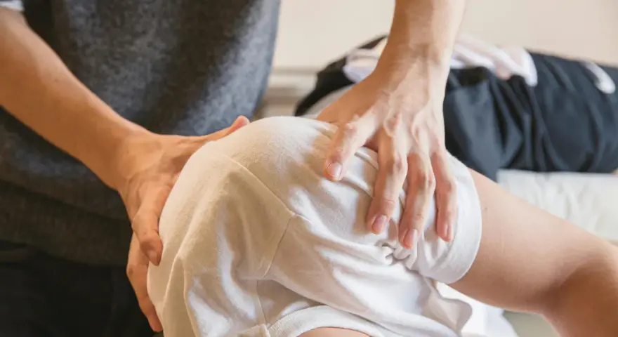 Fizjoterapeuta bada ramię pacjenta, szukając odpowiedzi na pytanie, czy uszkodzony nerw się regeneruje.