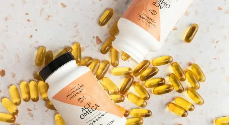 Dwie butelki i rozsypane kapsułki suplementu ACP Omega, zawierającego kwasy omega 3.